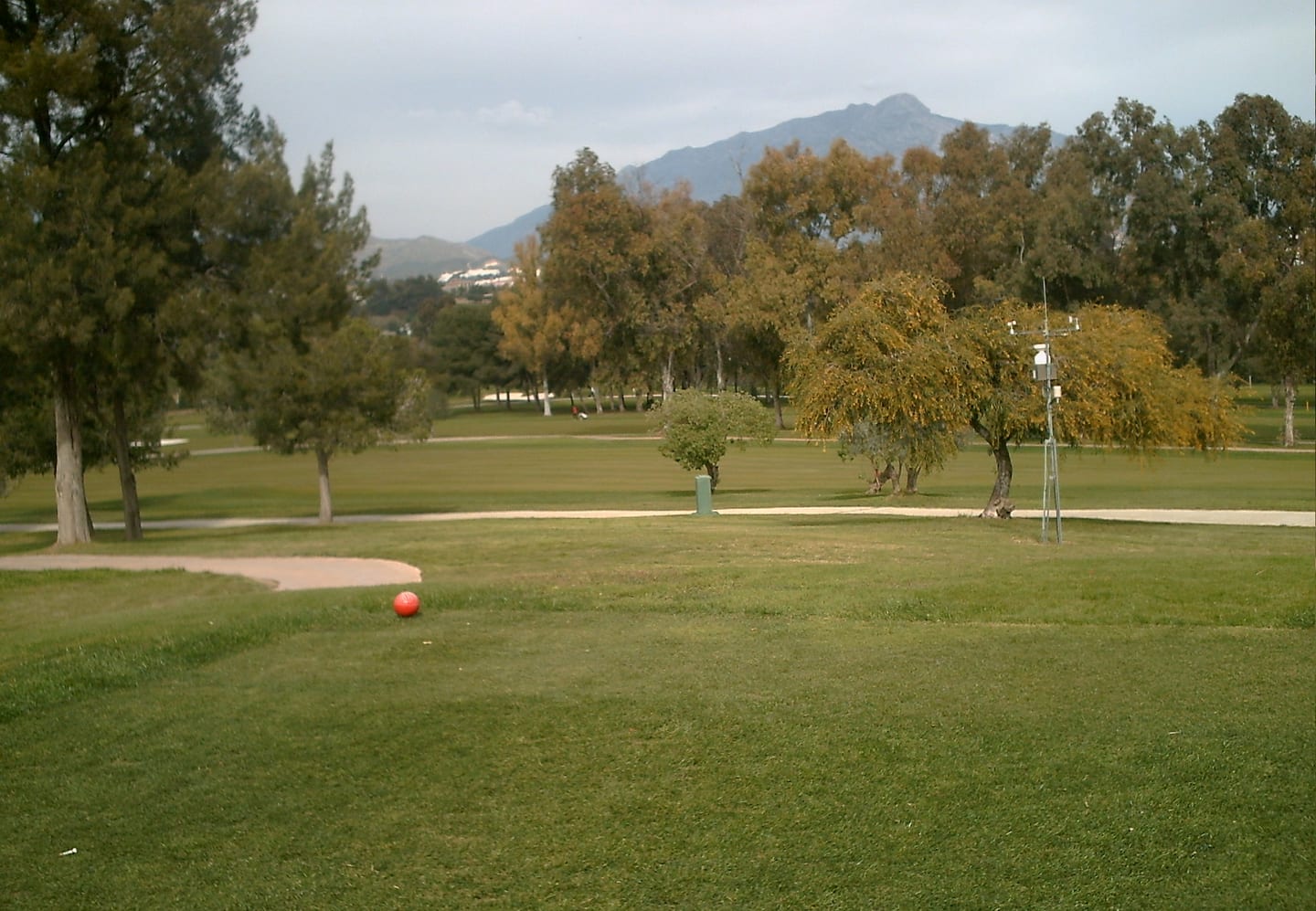 Atalaya golf course fairway with sand bunker, mature trees and Sierra Bermeja mountain backdrop, Estepona, Andalusia, shown as local context near SERENE ATALAYA II / III