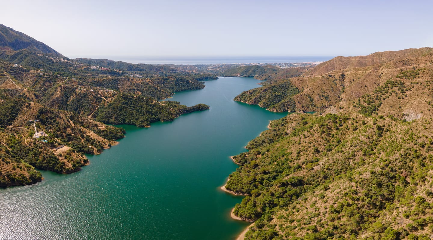 Embalse de La Concepción reservoir and Andalusian foothills near Benahavís, with the Mediterranean coast in the background, near VISTA LAGO RESIDENCES