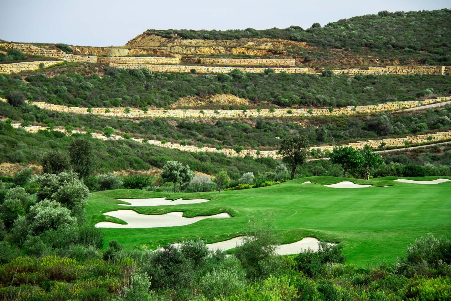 Golf course fairway with sand bunkers and terraced Mediterranean scrub hillside near Casares, Costa del Sol, shown as local context near VILLA COLOMBIA
