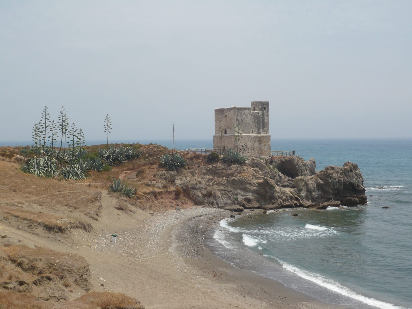 AUREA VILLAS area photograph of the Historic coastal watchtower (Torre de Bahía de Casares) on a rocky headland with the Mediterranean shoreline in Casares, Málaga, Spain.