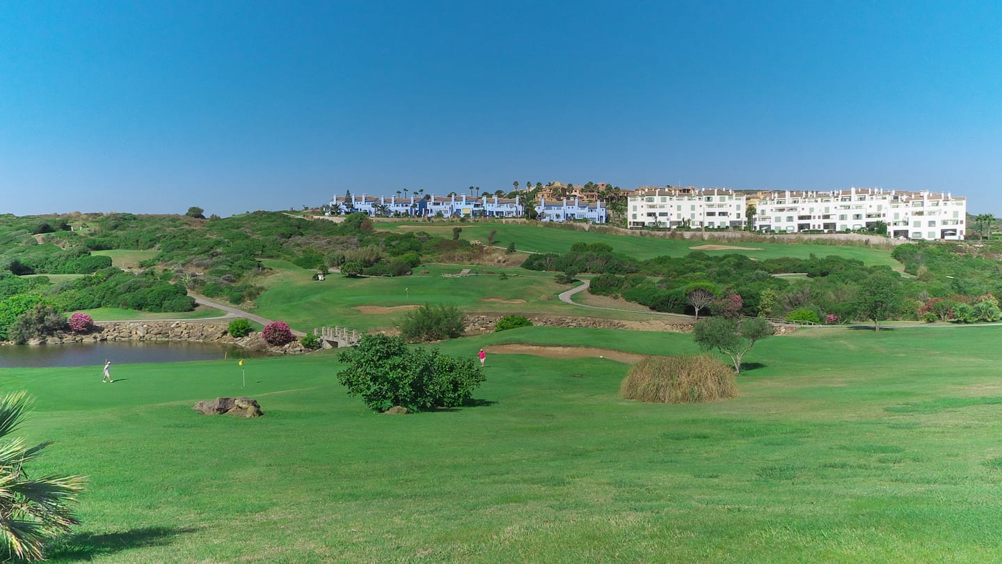 SERENITY FRONTLINE GOLF HOMES AND BEACH CLUB: La Alcaidesa Heathland golf course, Mediterranean landscape and distant residential buildings in La Alcaidesa, Costa del Sol