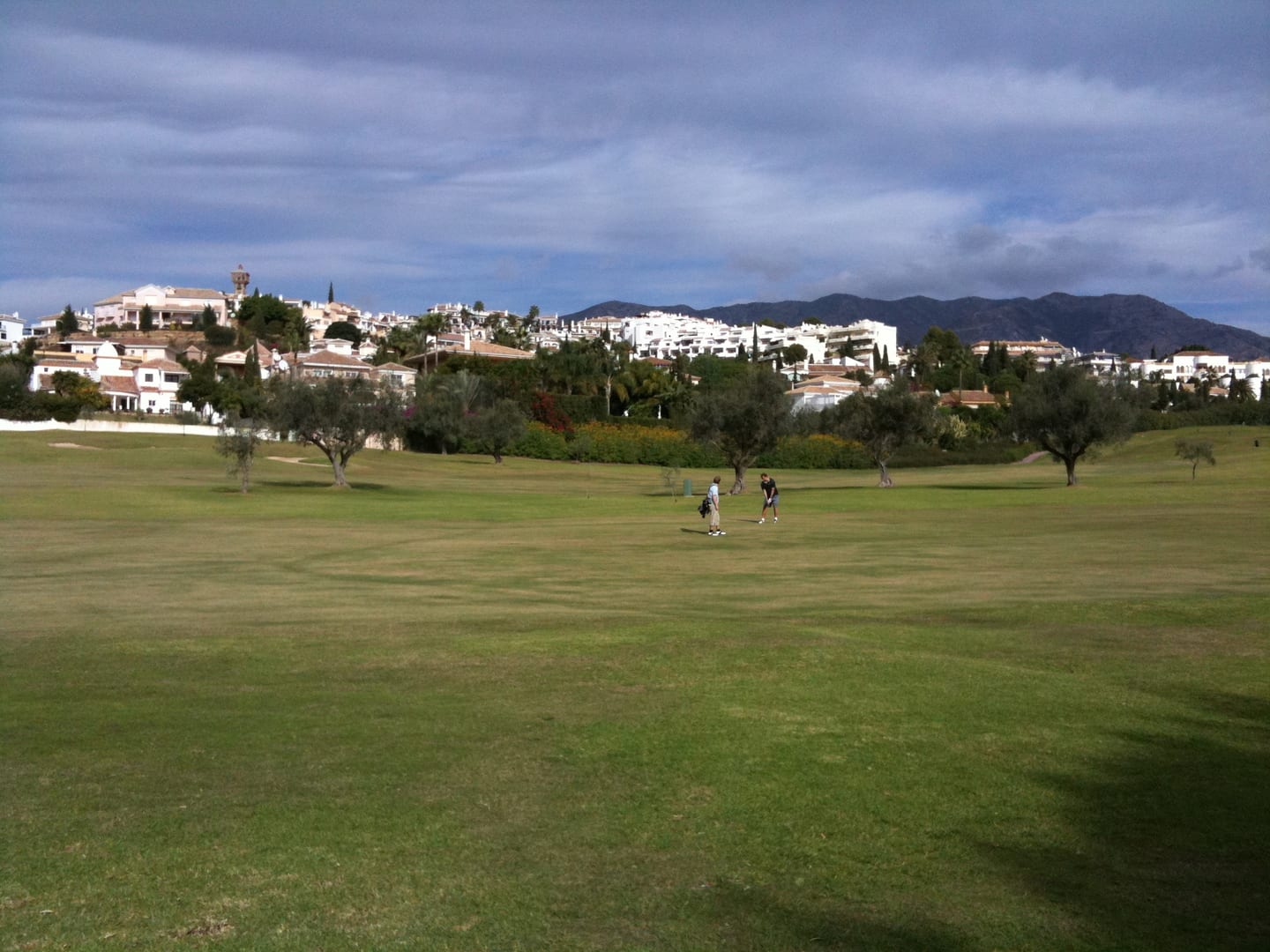 Los Olivos golf fairway with olive trees, Mijas Golf residential hillside, and Sierra de Mijas mountains — local area context for Mijas Golf, Costa del Sol, shown as local context near STUPA - VILLA SHANTI