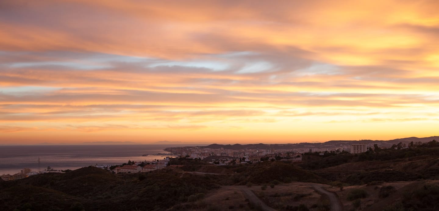 URBAN CITY HORIZON: panoramic elevated view of Fuengirola's coastal urban area, Mediterranean Sea and surrounding hills at sunset