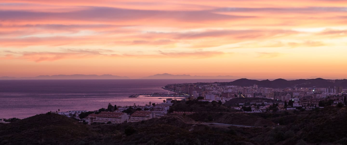 THE KOS: panoramic sunset view over Fuengirola's coastline, harbour, town and the Mediterranean Sea from the Higuerón hillside, Costa del Sol, Spain