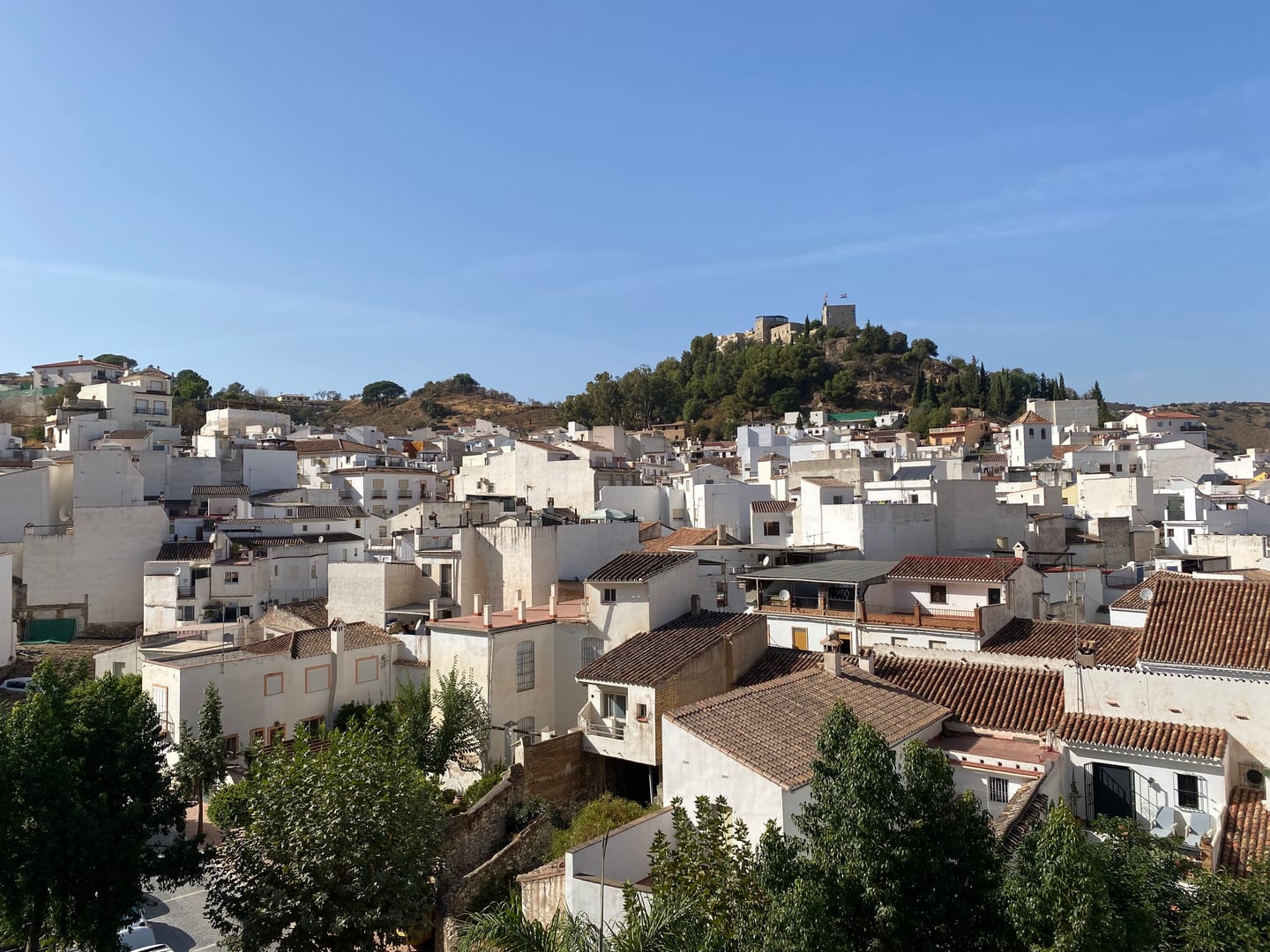 LUNA NOVA RESIDENCES area photograph of Monda village, showing whitewashed buildings and the hilltop castle/church in Málaga Province, Andalusia, Spain.