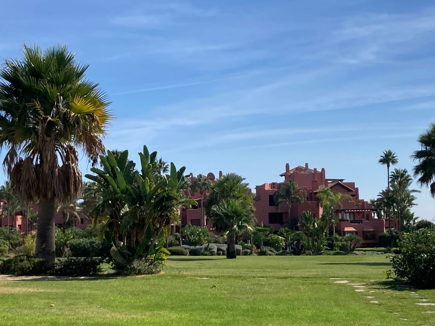 Area photograph near CAPRI - FASE 2 showing terracotta residential villas with tropical and Mediterranean landscaping in Estepona, Costa del Sol