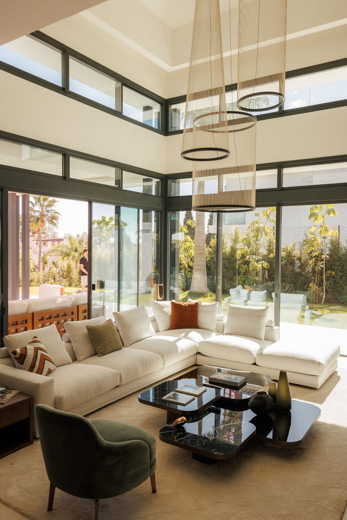 4OUR Villas: living room with light corner sofa, tall windows and pendant lights.