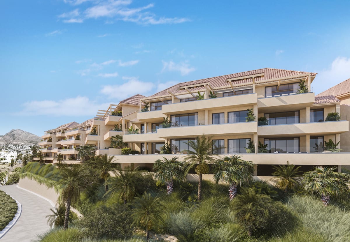 Project visualisation of ABELIAS with beige buildings, wide balconies with open railings, tiled roofs and palm trees lining a curved access road.
