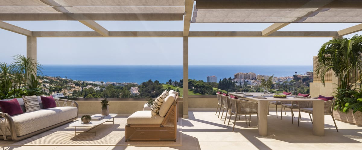 Project visualisation of the terrace at ABELIAS with a pergola, a lounge chair, seating area, dining table and views of buildings and the sea.