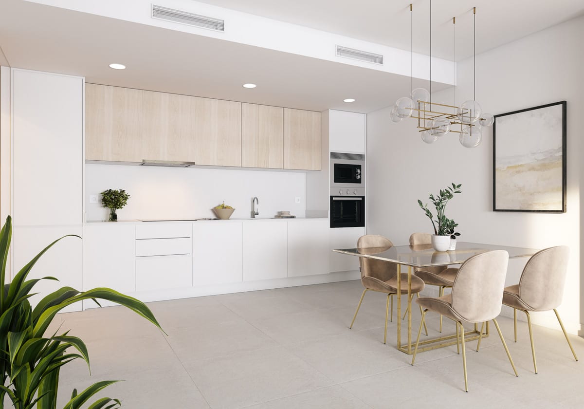 Interior visualisation of ABRIL DOÑA JULIA with a linear kitchen comprising white base cabinets, light wooden wall cabinets, built-in oven and microwave, extractor hood and sink, alongside a dining area with a dark-tinted glass table on gold legs and four beige velvet chairs.