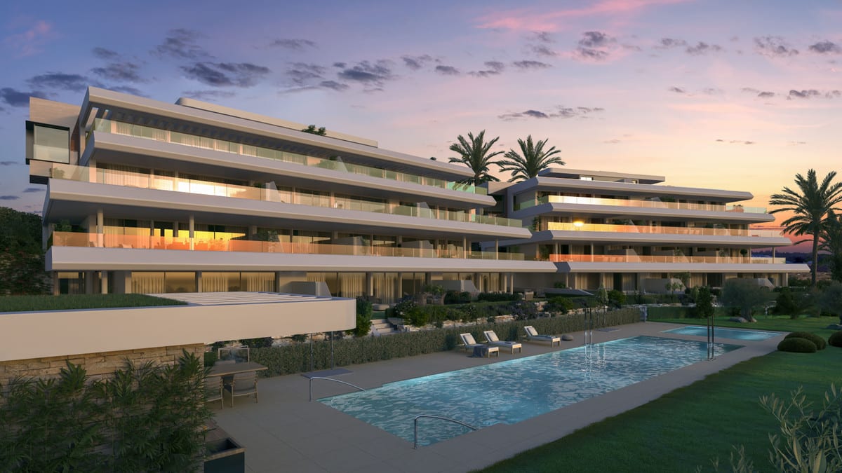 Evening rendered visualisation of ABSOLUTE ESTEPONA with illuminated glazed façades, wide balconies and a lit swimming pool in a green garden at sunset.