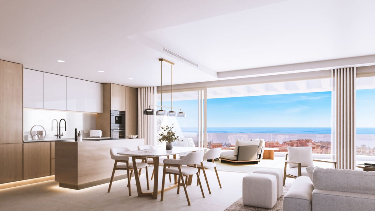 Rendered interior visualisation of ABSOLUTE ESTEPONA with a wooden kitchen, kitchen island, oval dining table and seating area beside sliding glass doors overlooking the horizon.