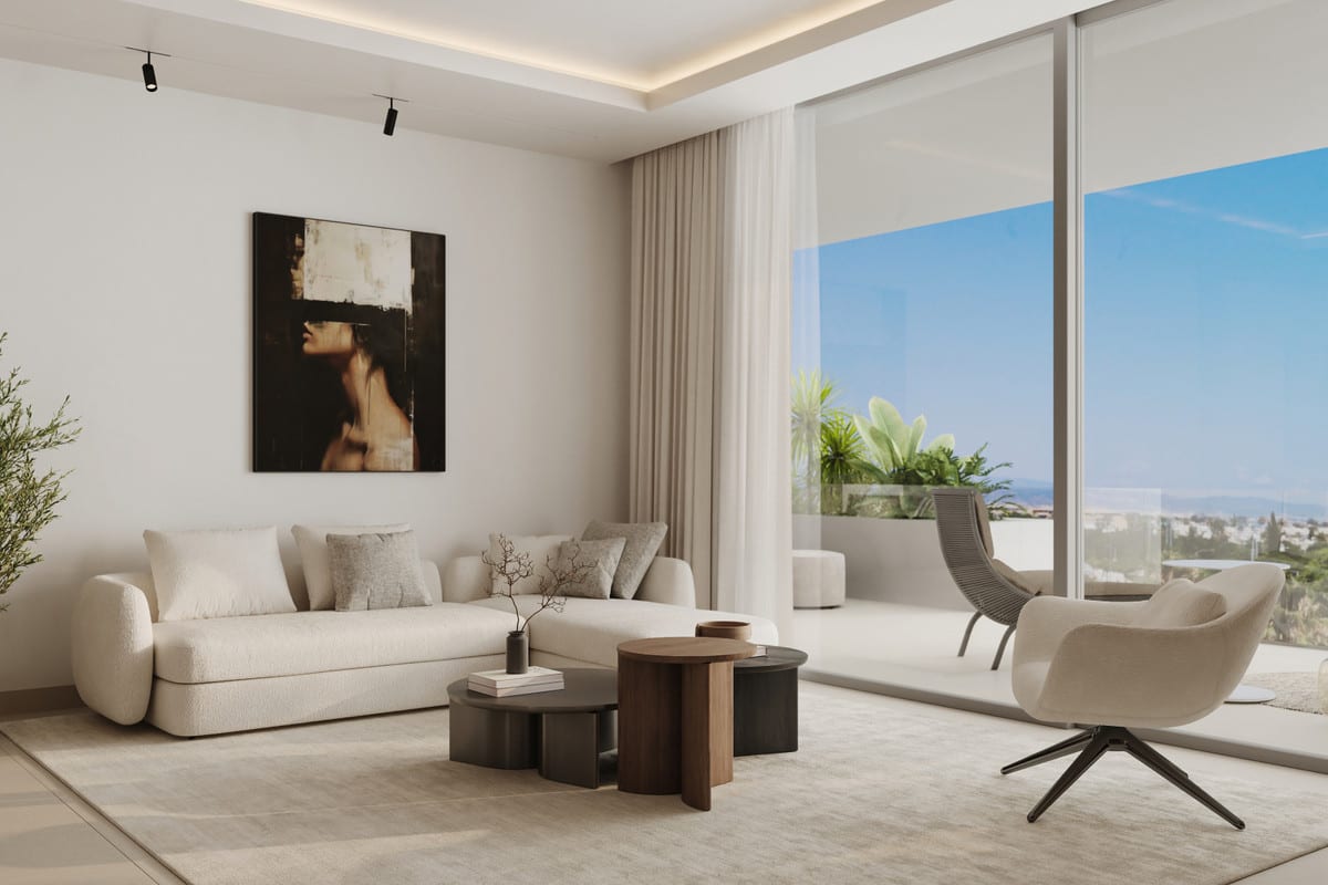 Project visualisation of ALCANTARA DEL MAR APARTMENTS showing a light seating area with a cream sofa, two organically shaped dark wooden coffee tables, a cream swivel armchair, a figurative painting on the wall and a large sliding glass door leading to a planted terrace with a glass balustrade.