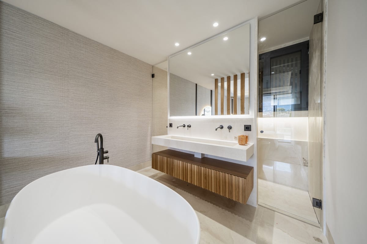Rendered bathroom with a freestanding bath, wood-effect vanity and glass shower screen.