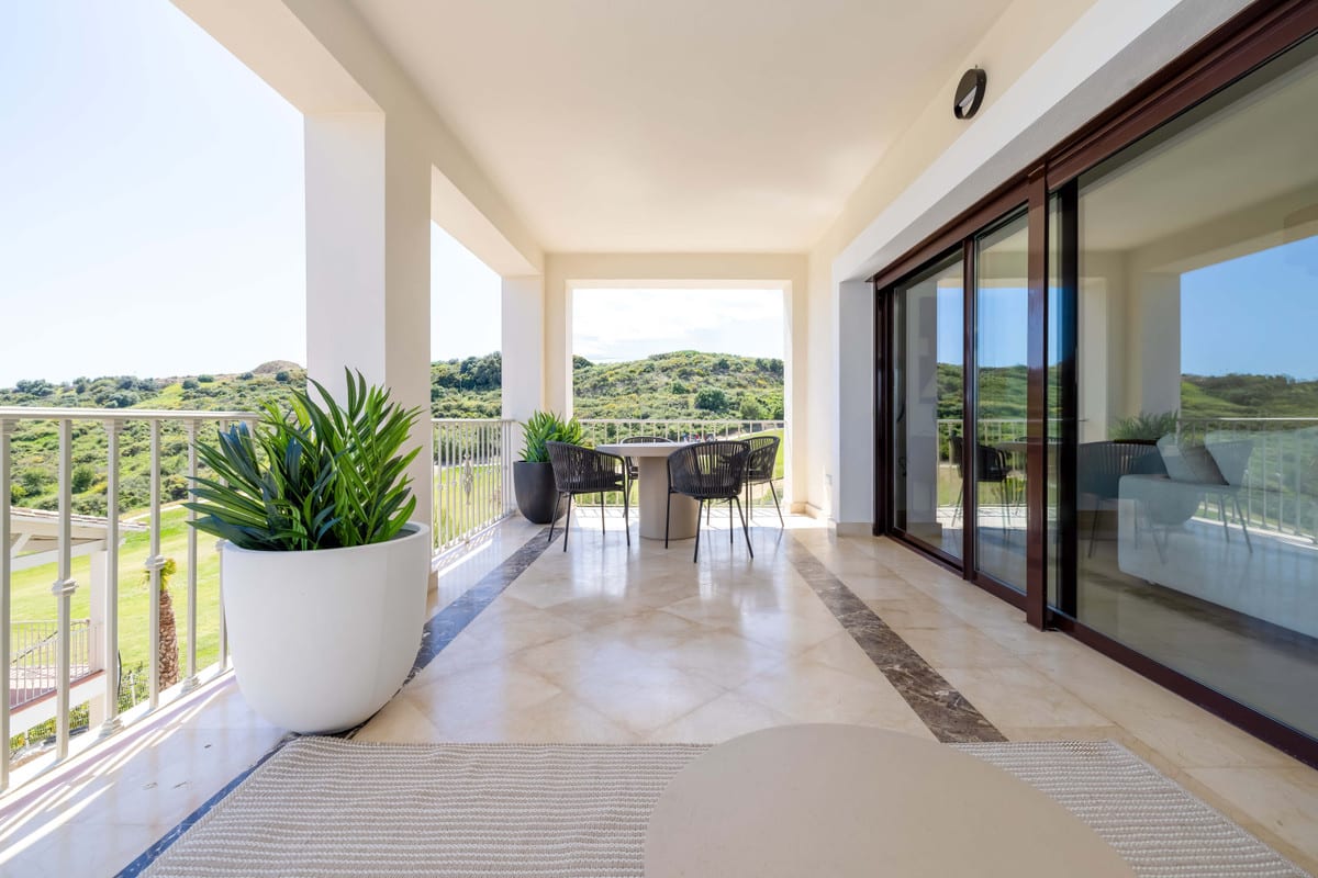 ALTOASIS: covered terrace with white columns, a table with chairs and large planters