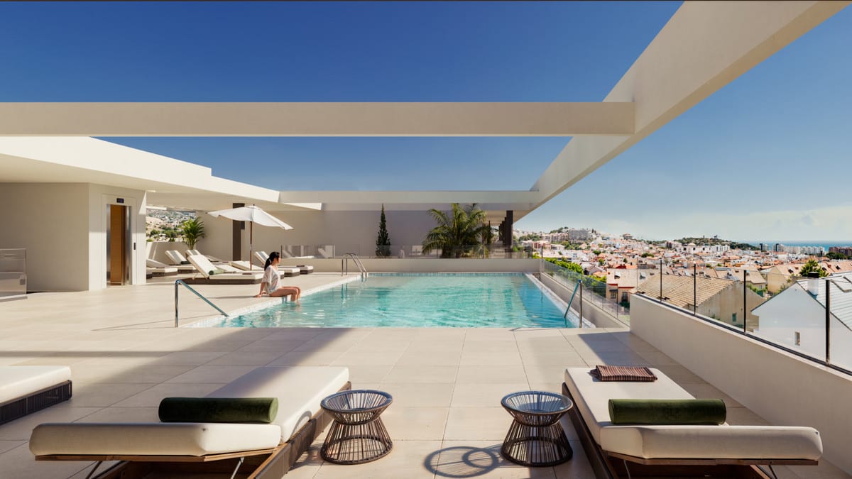 Rendered visualisation of the pool terrace at ASTRA HOMES featuring a rectangular swimming pool, sun loungers, a parasol, small side tables and a glass balustrade overlooking the surrounding buildings.