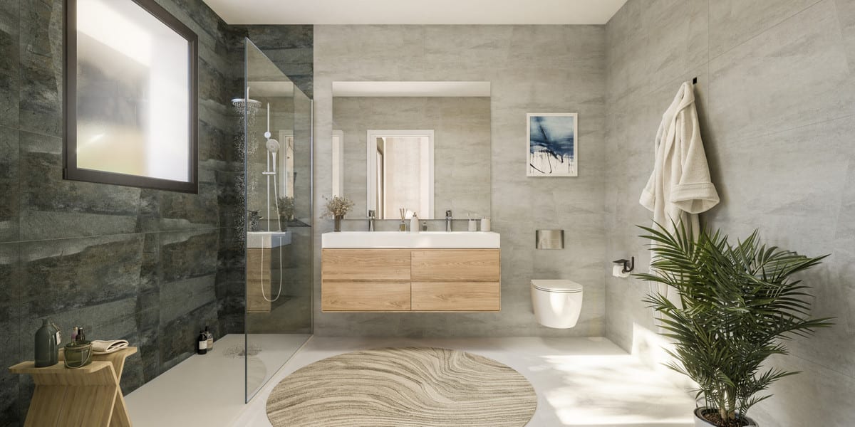 Project visualisation of ATTIRE ESTEPONA featuring a bathroom with dark stone-effect shower tiles, a frameless glass shower screen with rainfall shower, light-grey wall tiles on the remaining walls, a wooden floating vanity unit with double basin, a wall-hung toilet and a round rug.