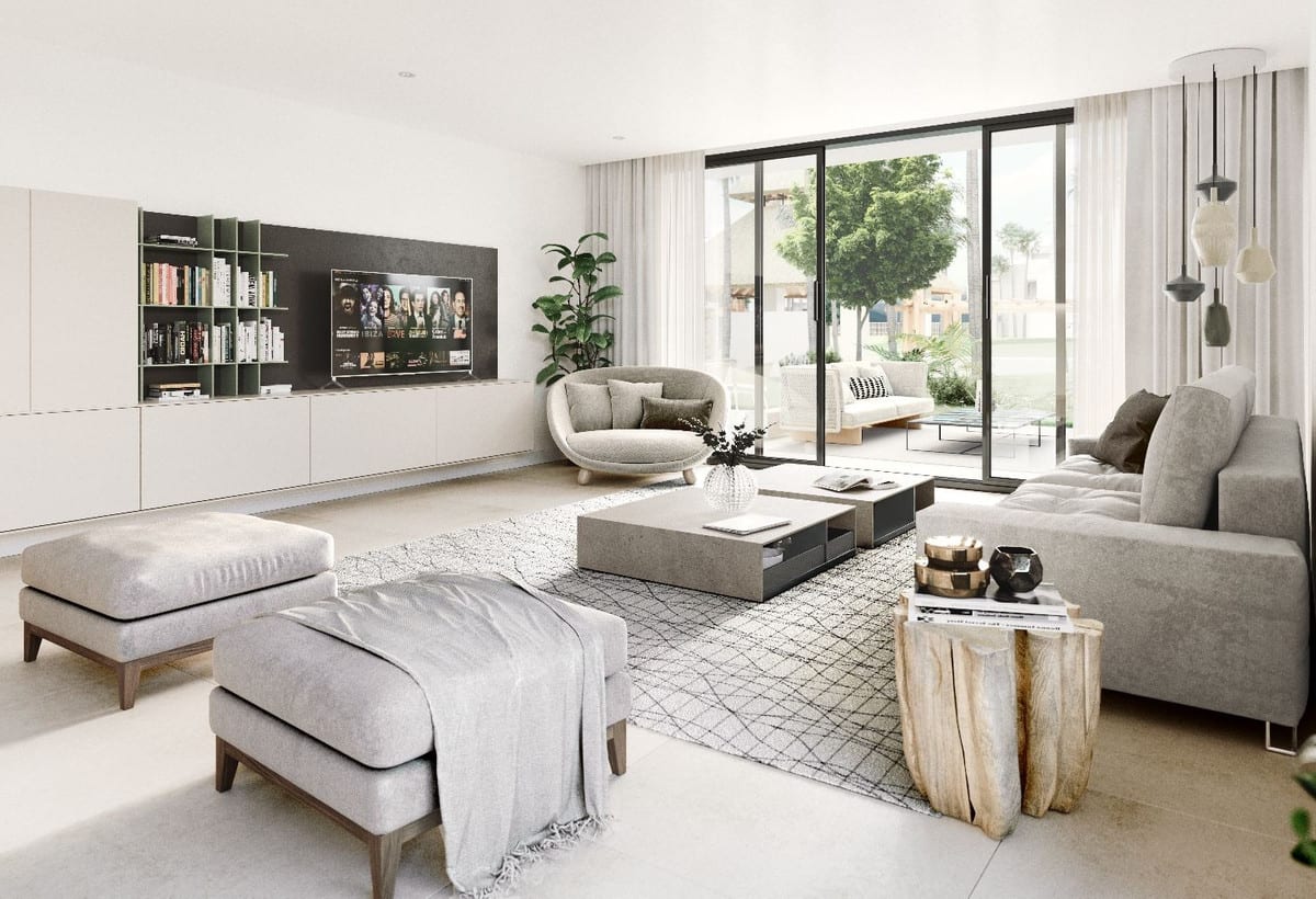 Project visualisation of AYANA ESTEPONA showing a bright living room with a grey sofa, a round armchair, a rug, a wall unit with TV and bookshelves, and sliding glass doors.