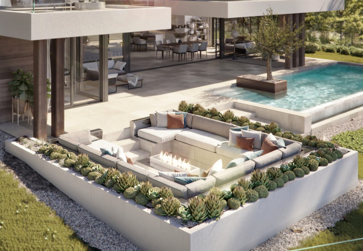A sunken outdoor seating area with a fire table and surrounding plants beside the pool.