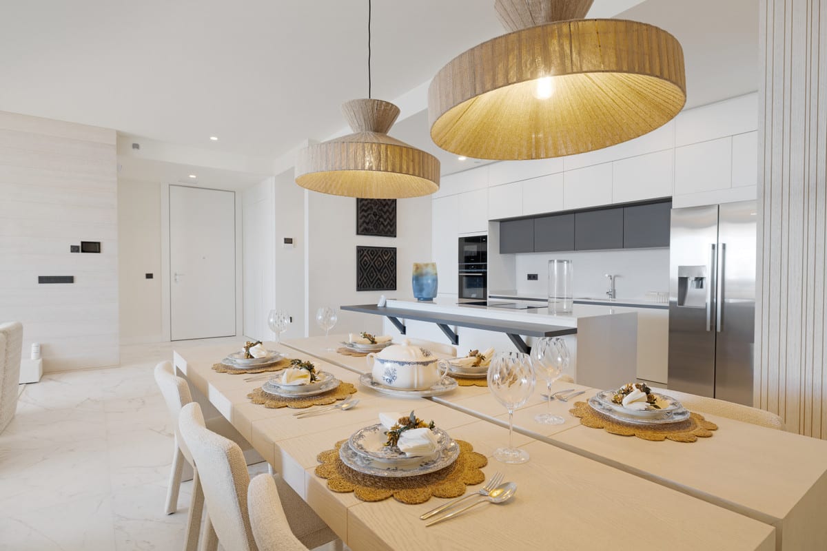 Dining area and open kitchen with wood-effect accents and woven pendant shades.