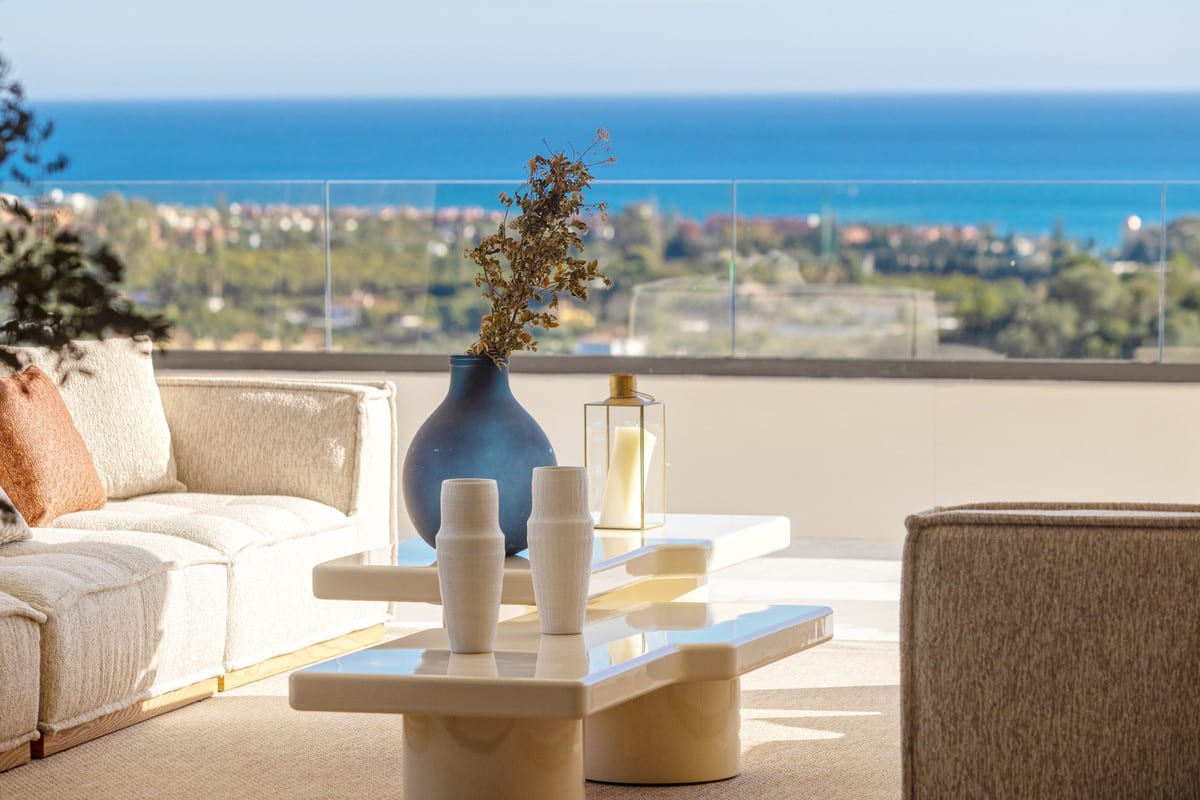 Terrace detail with decorative vessels and a lantern on the table, with the sea beyond the glass balustrade.