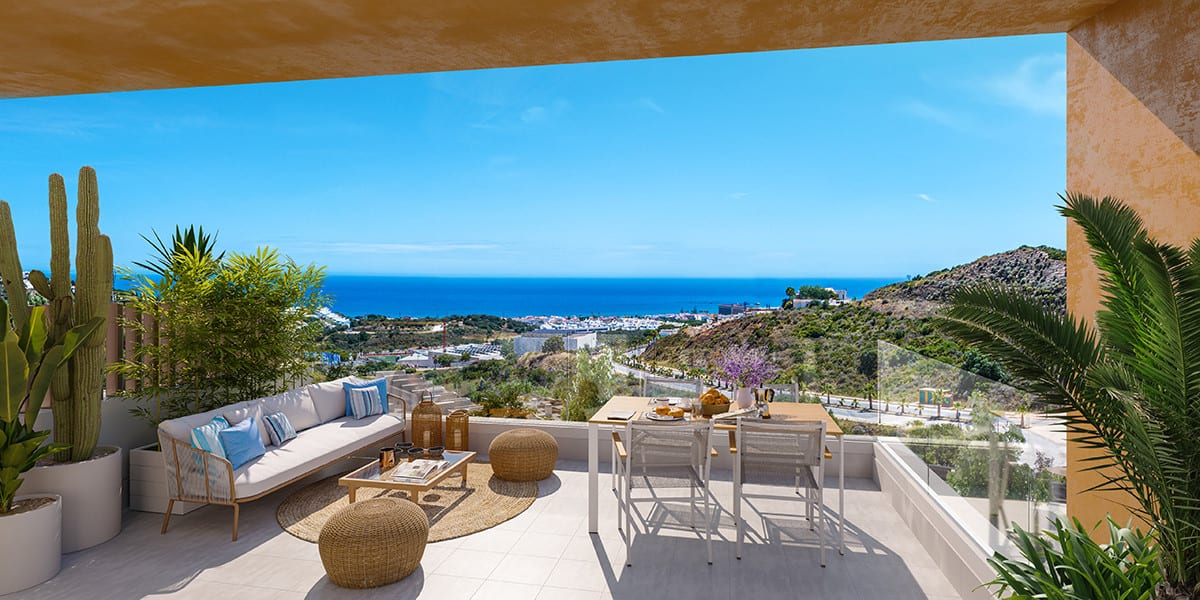 Project visualisation of the CALA SERENA SUN terrace with a white lounge sofa with blue cushions, rattan pouffes, a wooden coffee table, dining table with chairs, cacti and a glass balustrade overlooking hills and the sea.