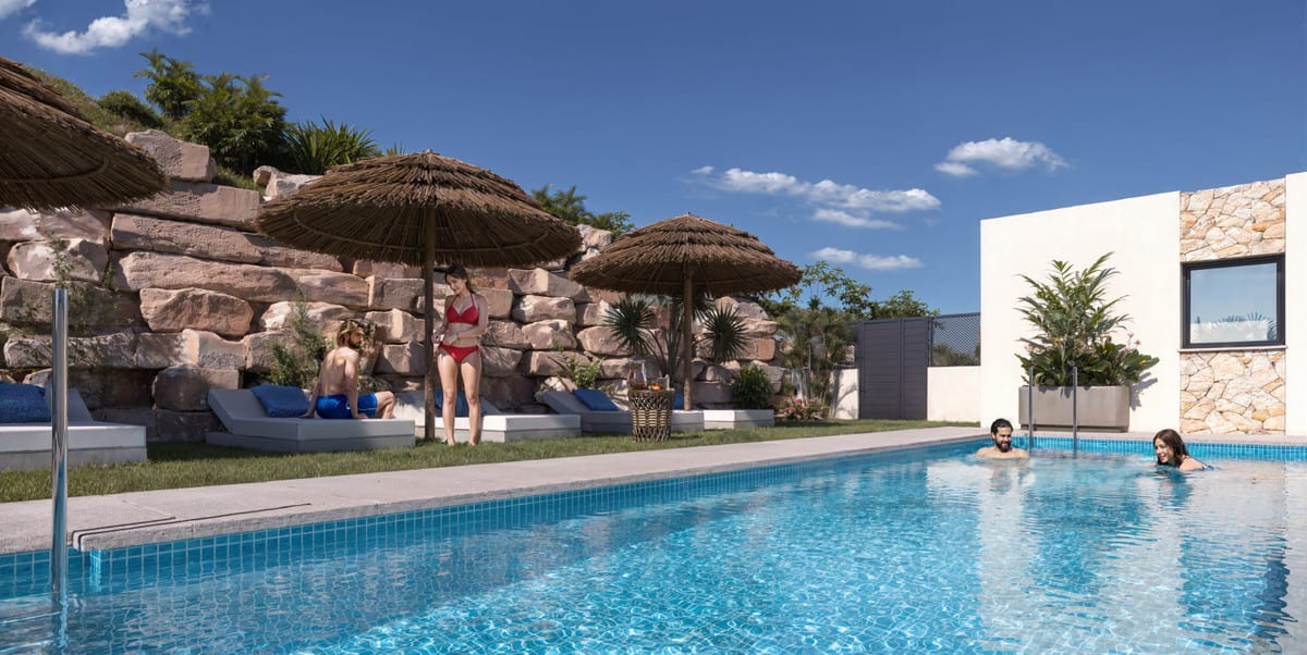 Project visualisation of CALAGOLF BY MARINSA with a blue swimming pool, straw parasols, grey sun loungers on grass and a natural stone wall.