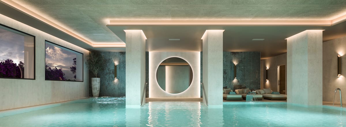 Project visualisation of CAPRI - FASE 2 featuring a covered indoor swimming pool, light-coloured columns with integrated lighting, wall lights and a round illuminated opening in the rear wall, with lounge furniture beyond.
