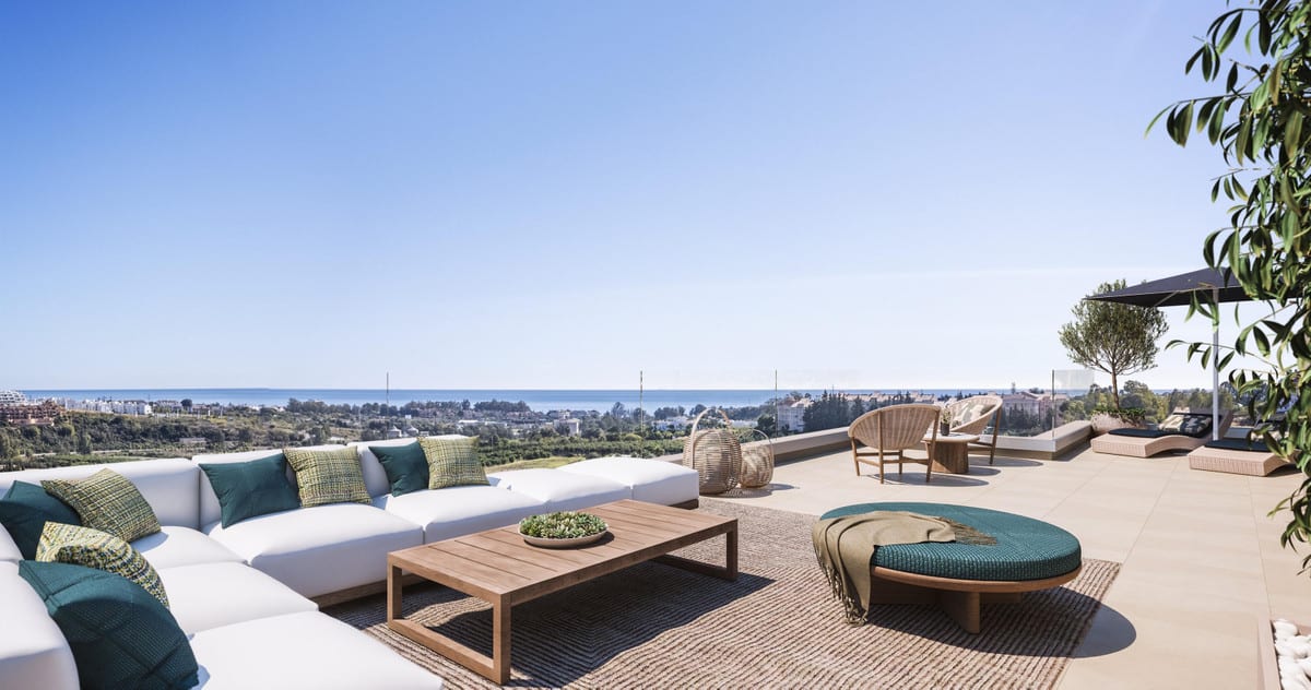 Project visualisation of CAPRI - FASE 2 featuring a spacious terrace, a white corner sofa with green cushions, a wooden coffee table, a round turquoise pouffe, a wicker armchair and open sea views on the horizon.