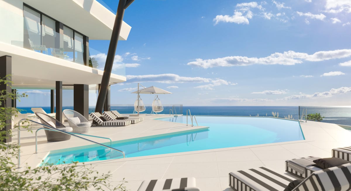 Project visualisation of CARAT with a large light-blue infinity pool, a light-tiled terrace, striped sun loungers, hanging egg chairs, a freestanding parasol and the sea on the horizon.