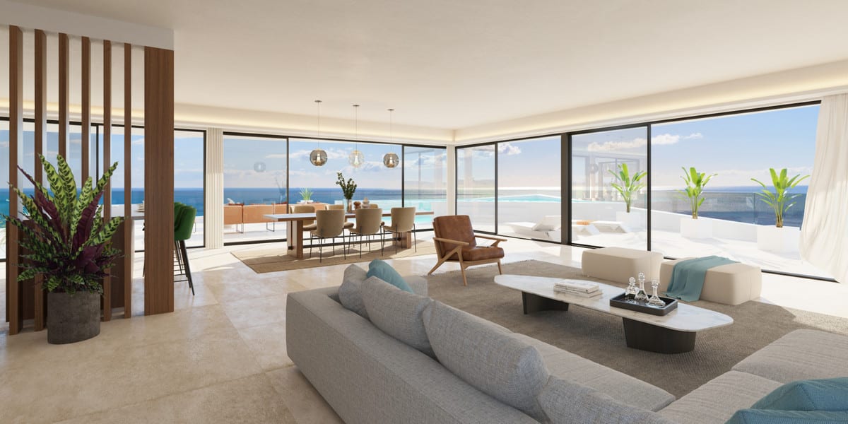 Project visualisation of CARAT with a bright living room, grey corner sofa, wooden slatted room divider, dining table with pendant lights and floor-to-ceiling glazing opening onto a terrace with a pool and sea views.