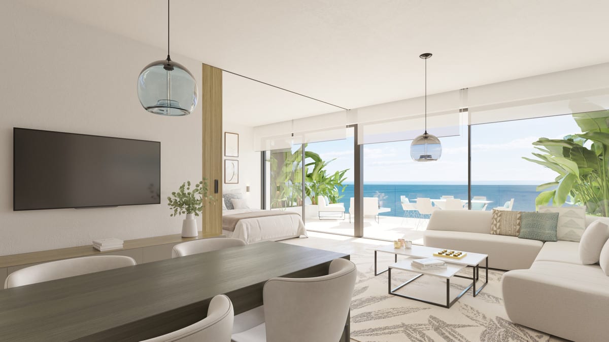 Project visualisation of CARAT with a dark wooden dining table, white curved banquette, wall-mounted television, blue glass pendant lights and glass sliding doors opening onto a terrace with the sea in the background.