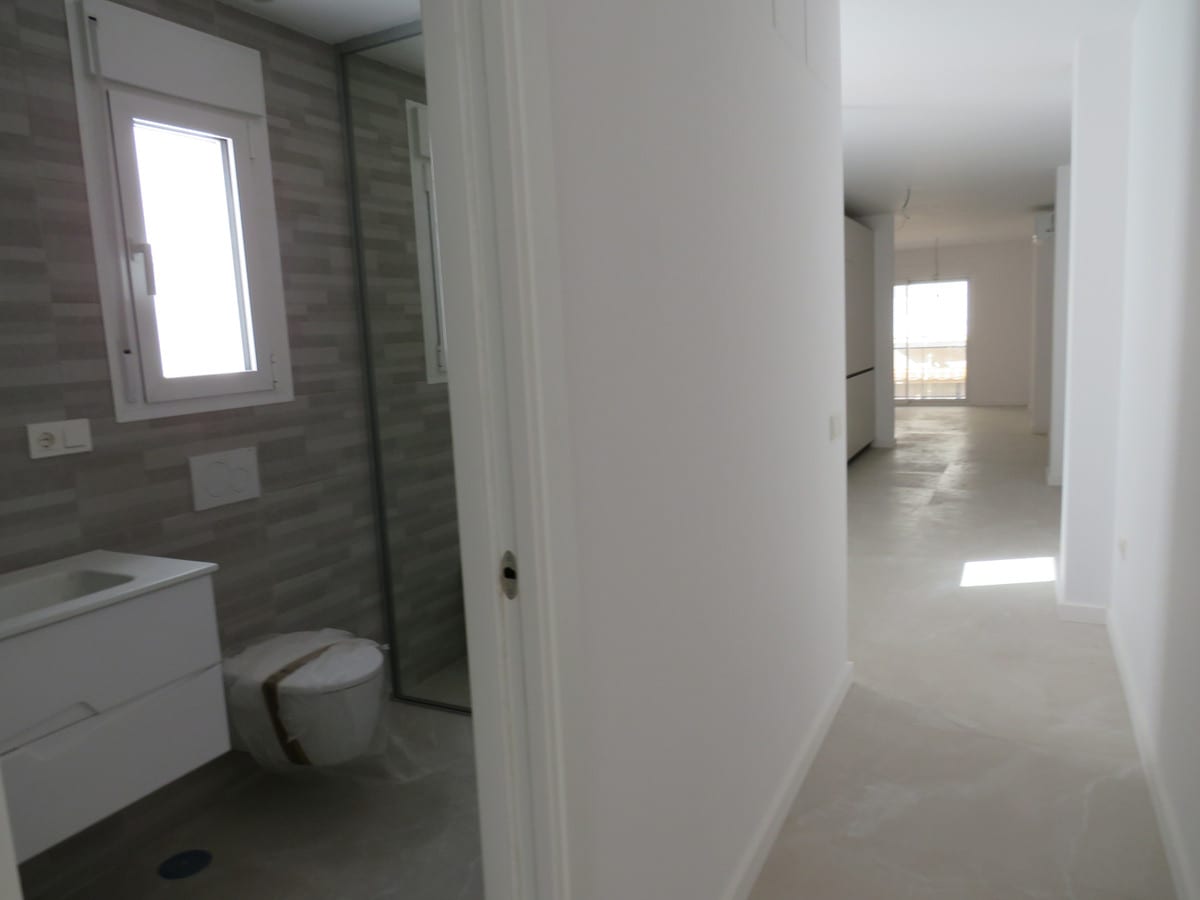 Bathroom and hallway at EDIFICIO VENECIA with grey wall tiles, a shower enclosure, washbasin and toilet.