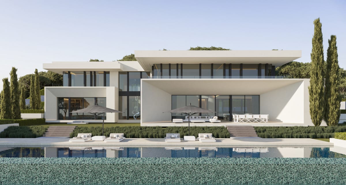 Poolside front view of VILLA STONEHAVEN with white facades, covered terraces, loungers and cypress trees.