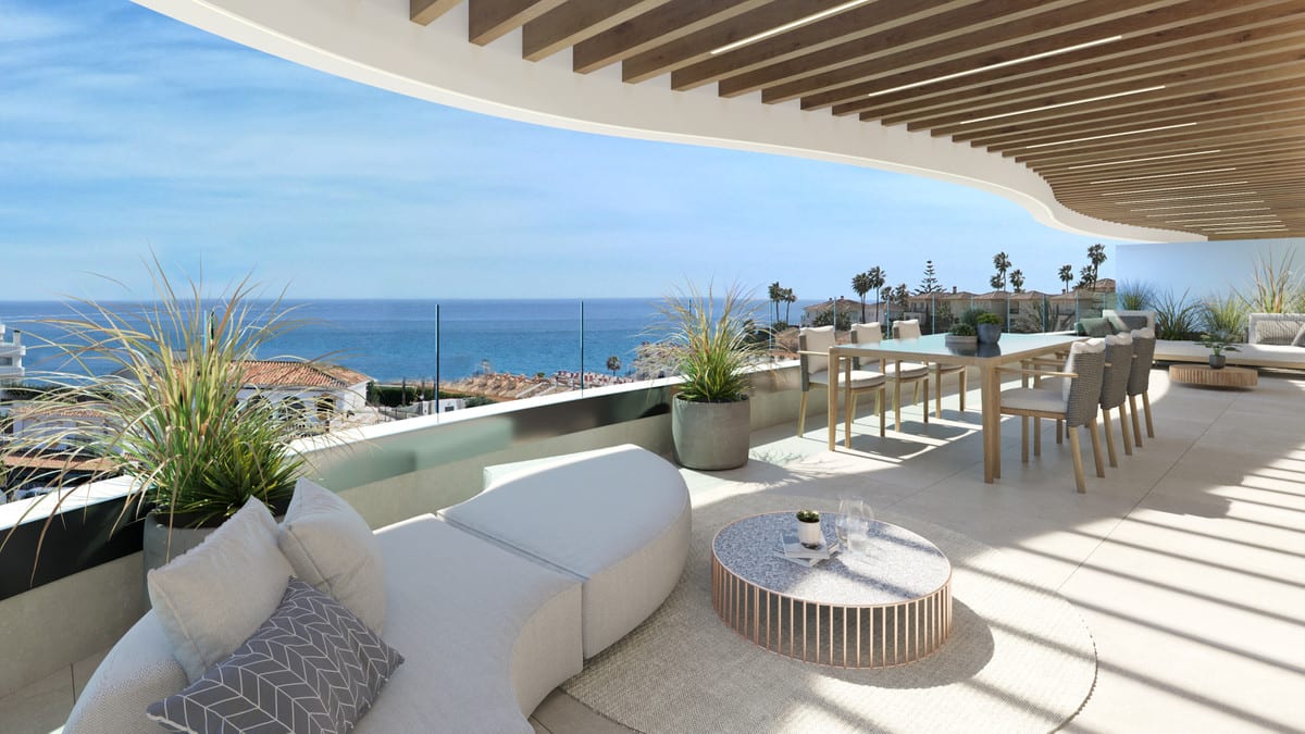 Project visualisation of ELYSEA SUITES with a spacious terrace beneath a canopy with wooden slats, a lounge daybed, round coffee table, dining table with chairs, planters and sea views.