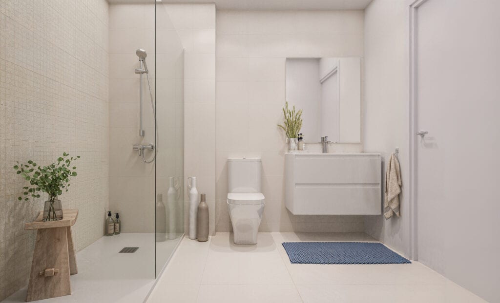 Az ETHERNA HOMES II fürdőszobájának belső látványterve üveg zuhanyfallal, zuhanycsappal, álló WC-vel, lebegő mosdószekrénnyel, tükörrel és kék fürdőszobaszőnyeggel.