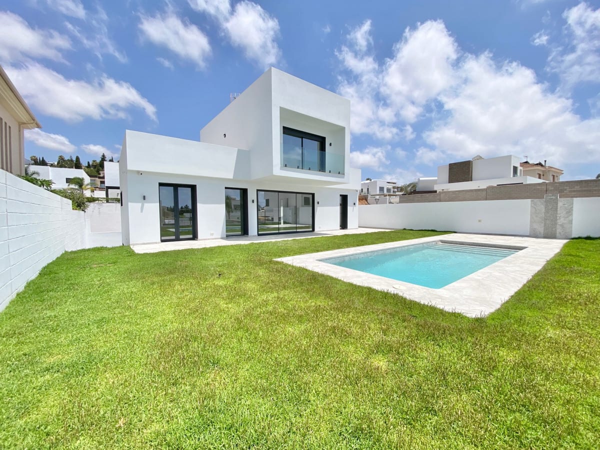 Wide garden view with lawn, pool and a white façade with dark-framed windows and doors.