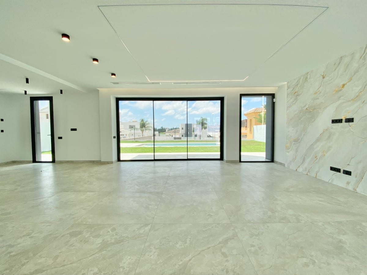 Unfurnished living space with large grey floor tiles, sliding doors to the garden and a stone-look feature wall.