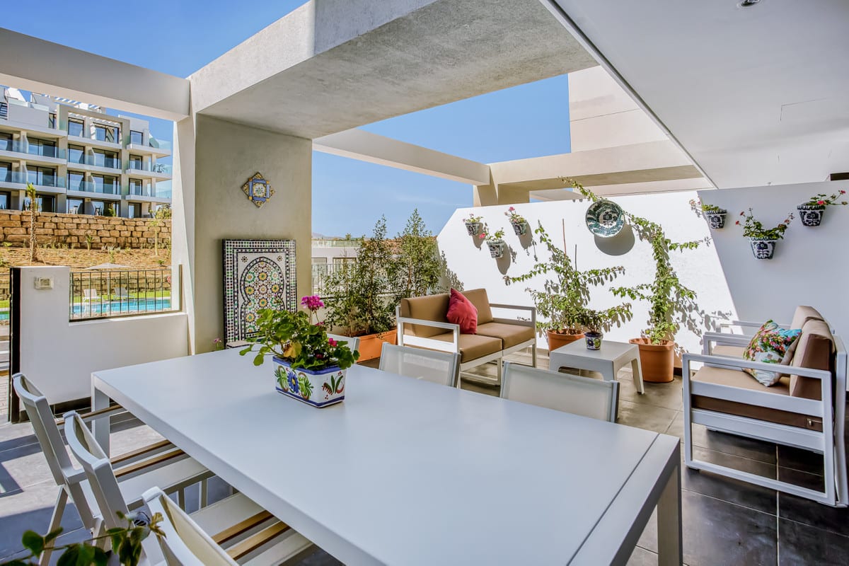 HACIENDA EL SUEÑO with a partially covered terrace, white dining table, seating area, planters, and decorative ceramic wall tiles and pots.