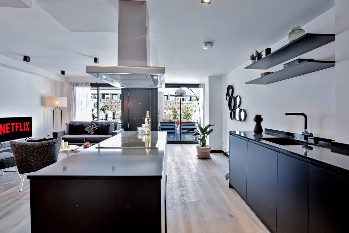 HACIENDA EL SUEÑO with a dark open-plan kitchen, large island with extractor hood, black sink, living room with sofa and terrace doors opening onto a terrace.