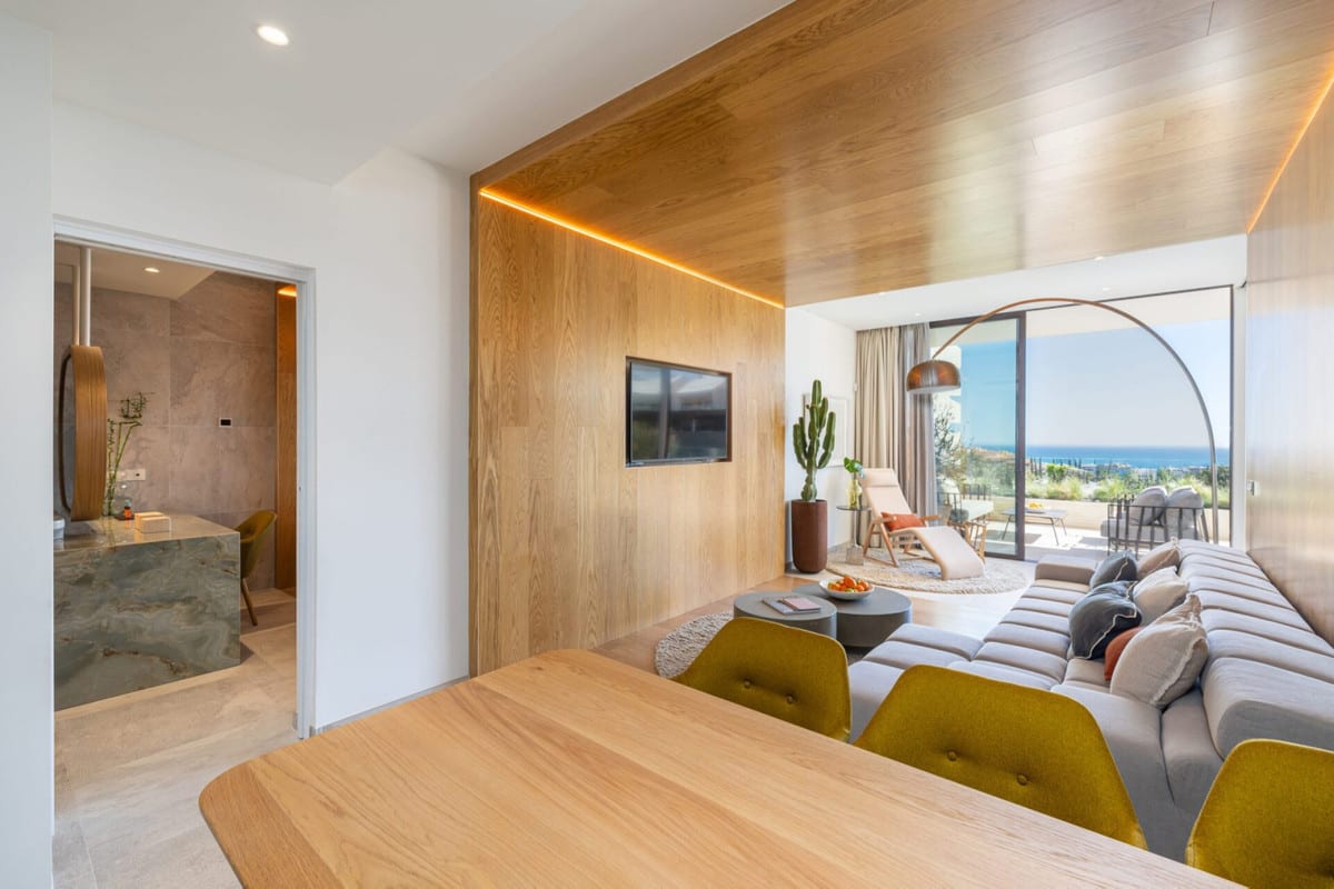 View of a living and dining area with wood panelling, a television and glazed doors to the terrace.