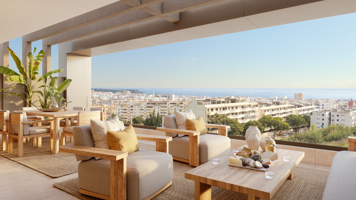 Project visualisation of LAS MESAS INFINITY HOMES featuring a covered terrace, wooden seating area and dining table, overlooking buildings and the sea in the distance.