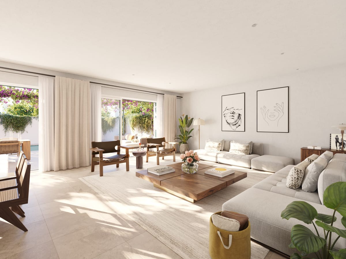 Project visualisation of LAS VILLAS–SOTOGRANDE featuring a large light-coloured corner sofa, wooden armchairs, wooden coffee table, two framed line drawings on the wall and opening sliding doors leading to a planted outdoor area.