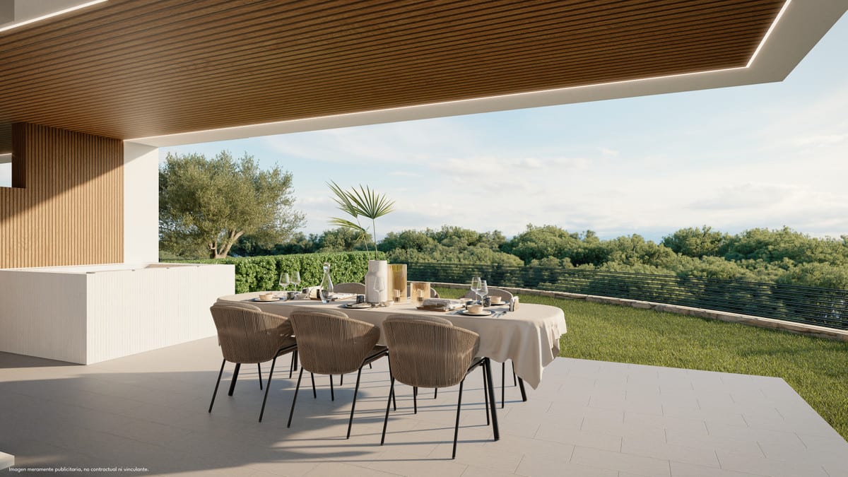 Project visualisation of the covered outdoor terrace at LOMAS UNIQUE A, with a laid dining table for six, a wooden slatted ceiling with integrated lighting and a lawn with green trees in the background.