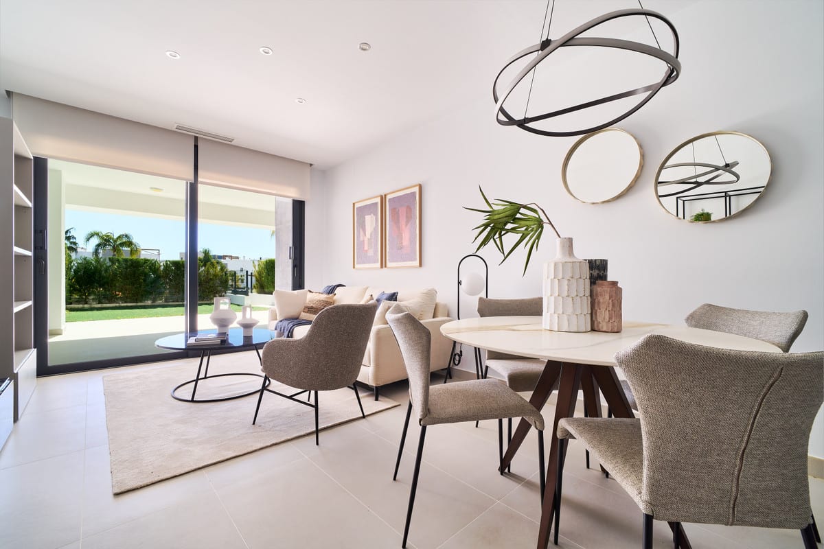 LOS MIRADORES DEL SOL with a furnished living and dining area, round light dining table, upholstered chairs and sliding glass doors leading outside.