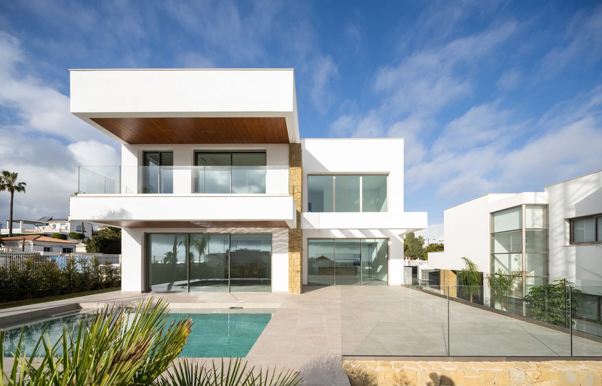 Rear façade with sliding glass doors, a terrace with glass screening and a rectangular pool.