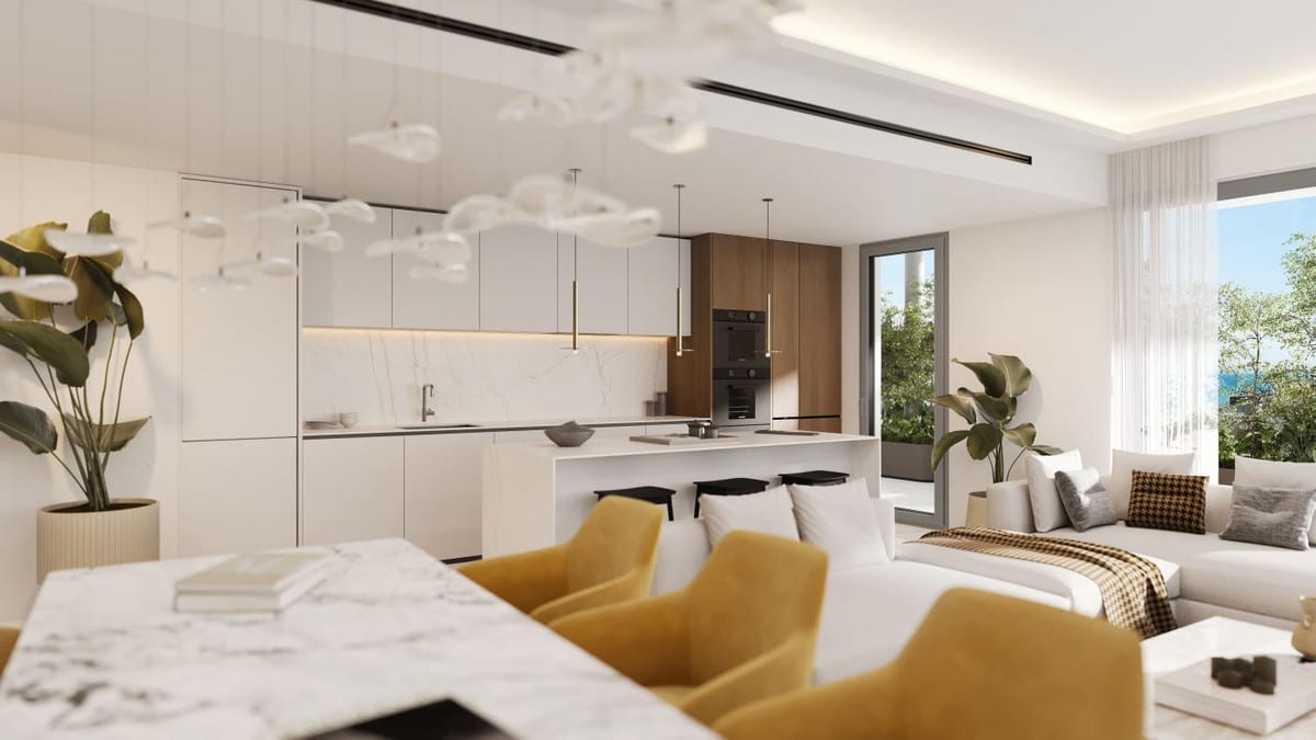 Interior visualisation of MACAN BEACH RESIDENCES with a white kitchen, wooden wall cabinets, a kitchen island with a marble-effect worktop and an open seating area with yellow chairs.