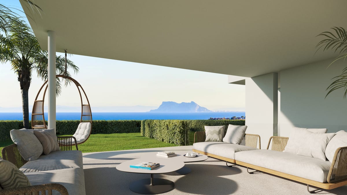 Project visualisation of MARBELLA CLUB HILLS PHASE II with a covered outdoor lounge, light-coloured sofas, a hanging chair, green lawn, hedge and the sea in the background.