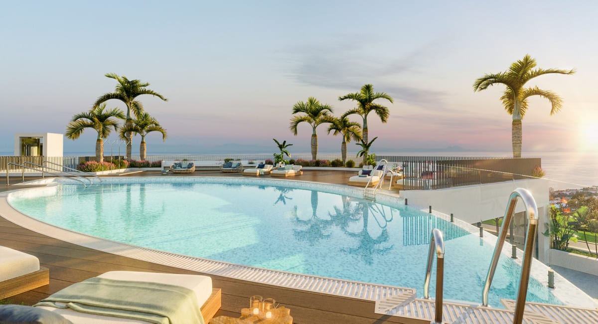 Project visualisation of MEDBLUE I, II & III with an oval outdoor swimming pool, wooden deck, sun loungers, palm trees and a metal balustrade.
