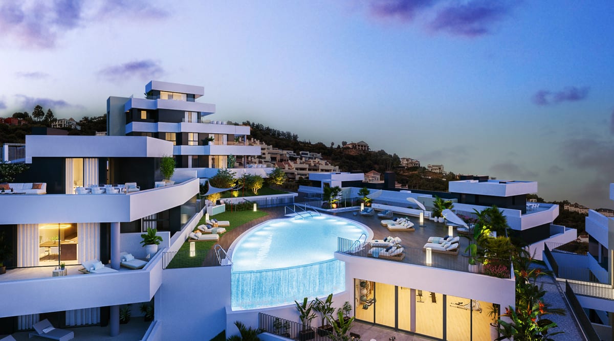 Evening visualisation of MEDBLUE I, II & III with illuminated buildings, an outdoor swimming pool, terraces and seating.